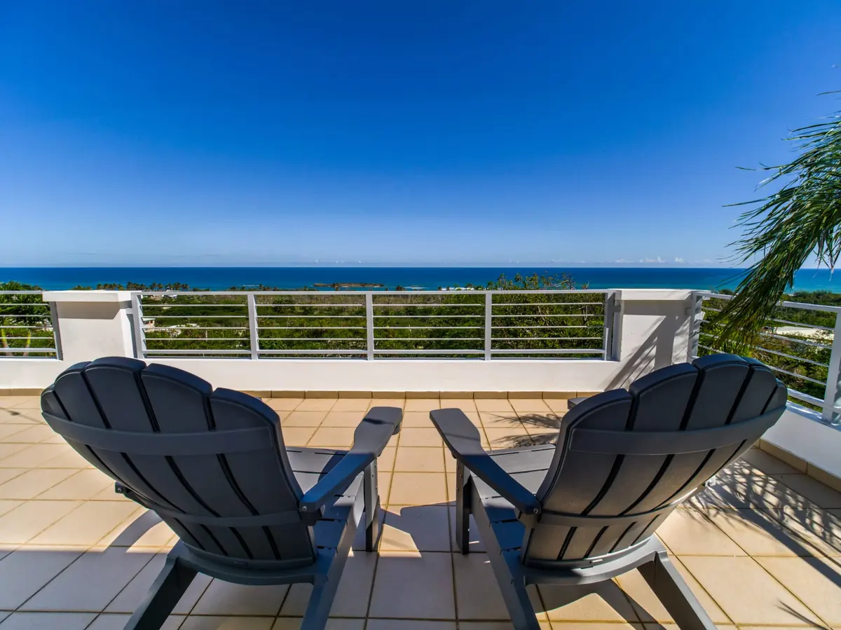 Two grey chairs on the balcony facing the ocean and the small island offshore