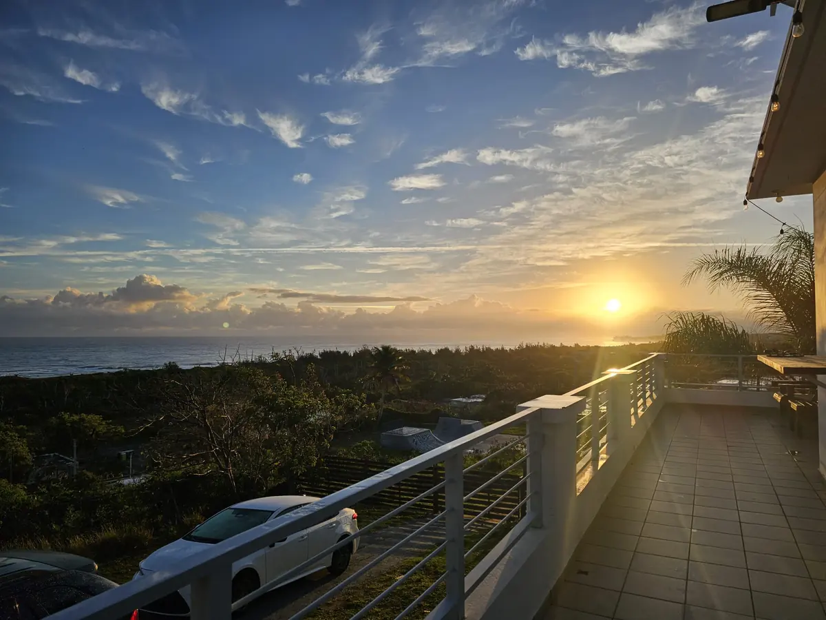 Sunrise over the Atlantic from the balcony of The House on the Cliff, string lights along the roofline